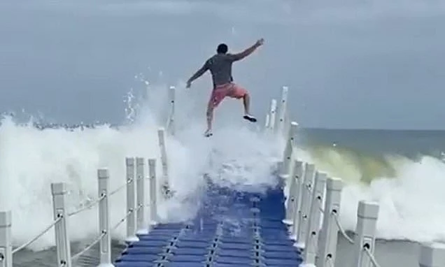 Daredevils leap over breakers as they run along floating platform at beach resort